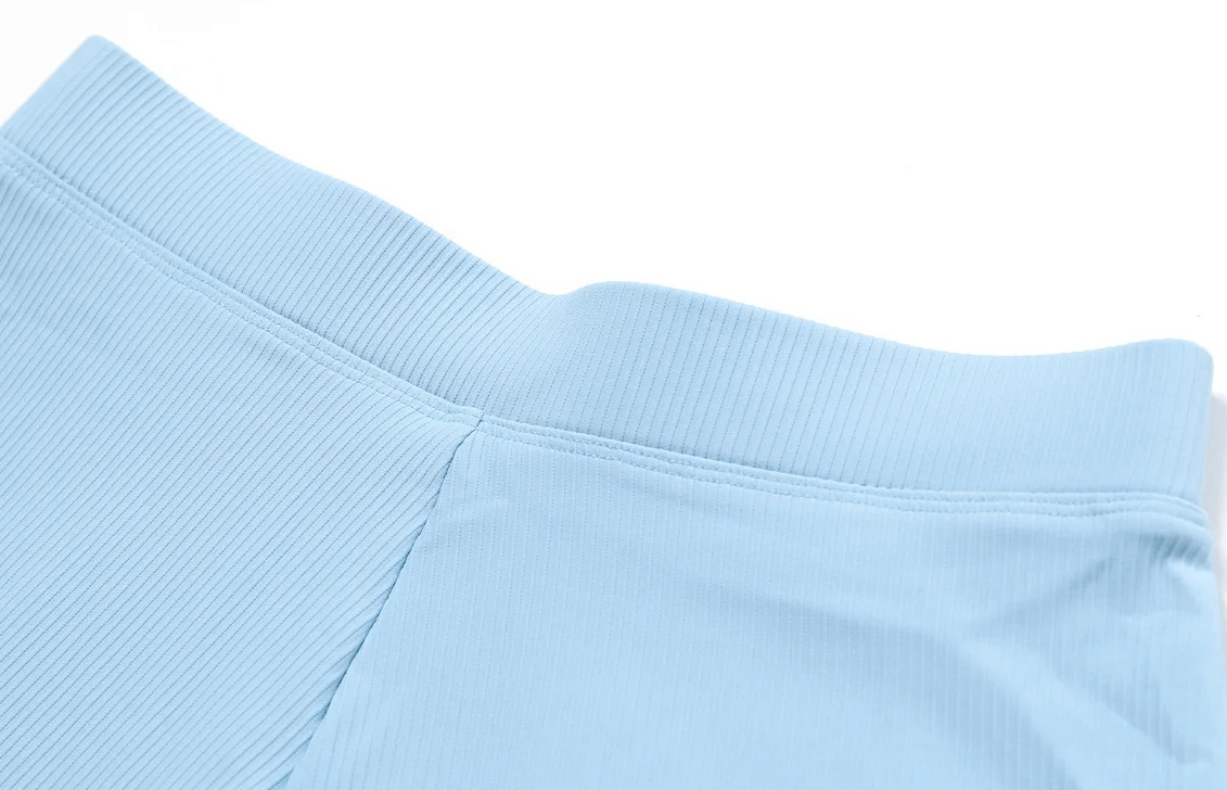 Close-up of blue ribbed waistband on performance high waist workout shorts for women, showcasing breathable moisture-wicking fabric.